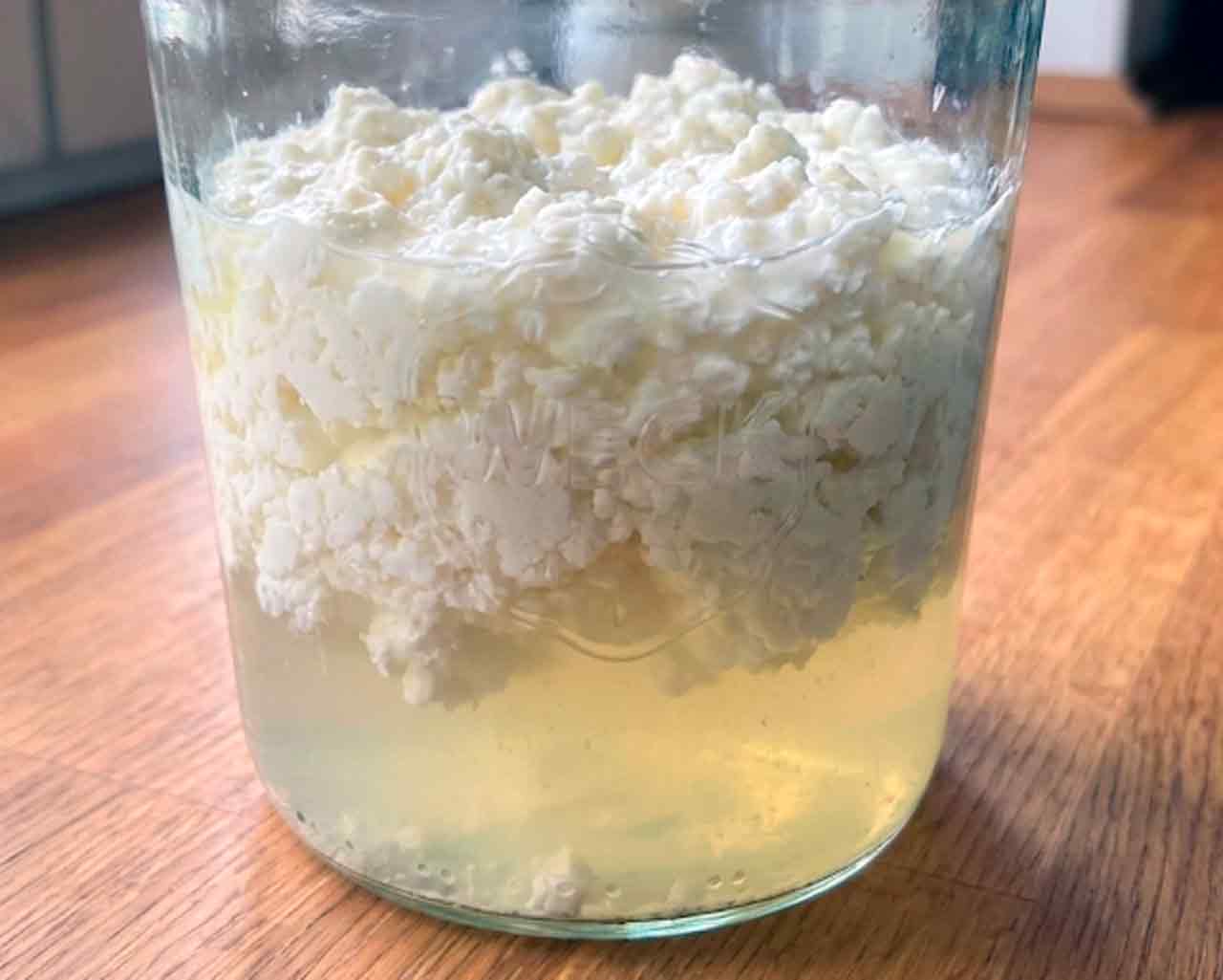 Geschifte melkkefir met een dikke laag wrongel bovenop en gelige wei onderop